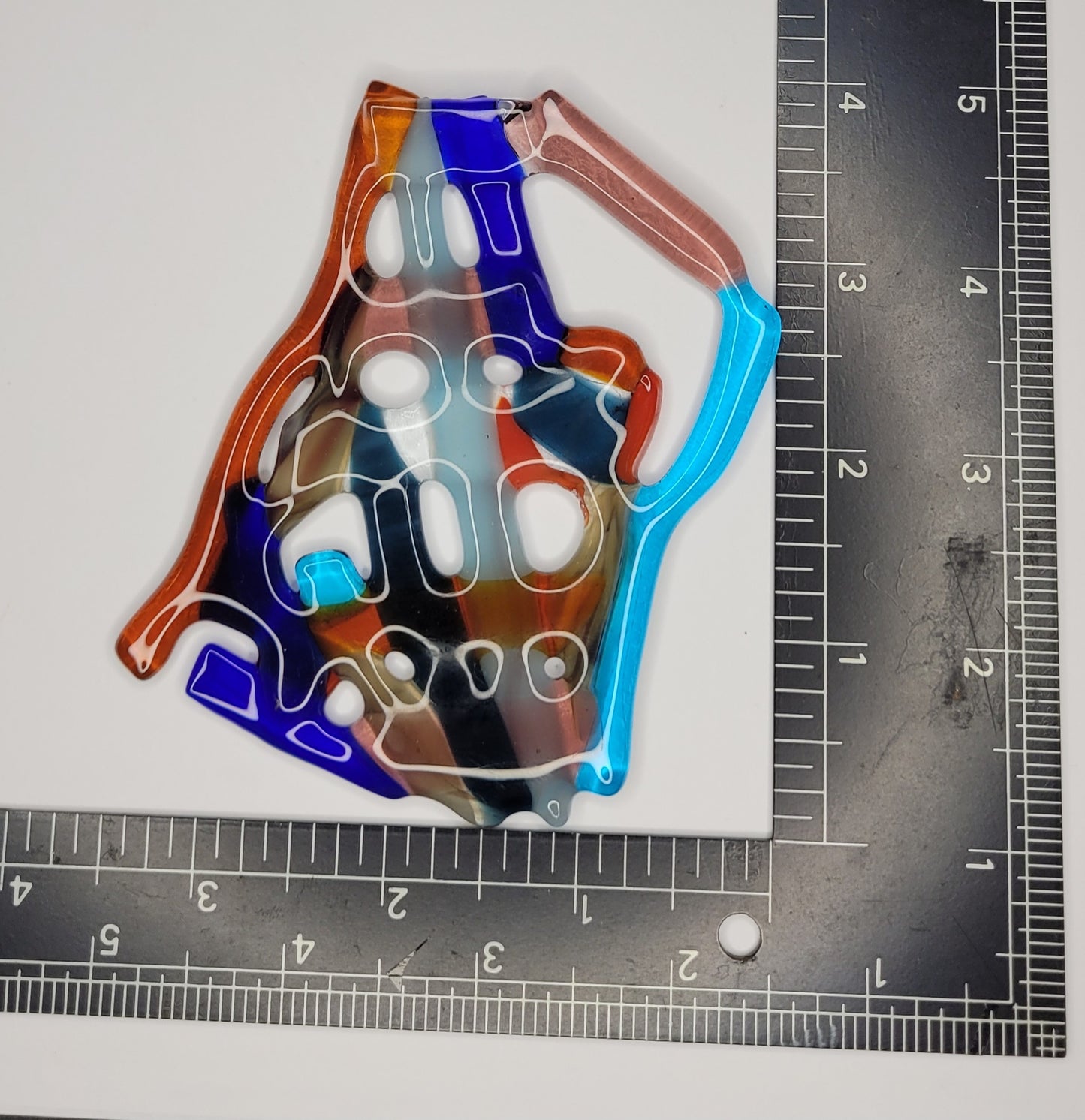 Colorful glass suncatcher on a white background with a ruler for scale.