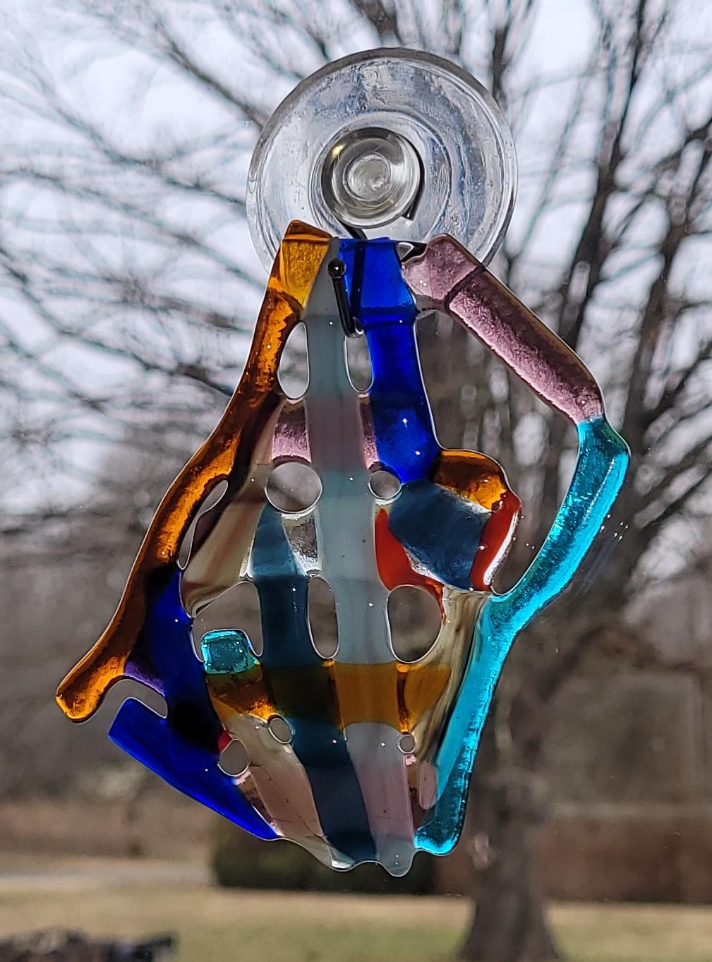 Colorful glass sun catcher with a suction cup against a blurred outdoor background