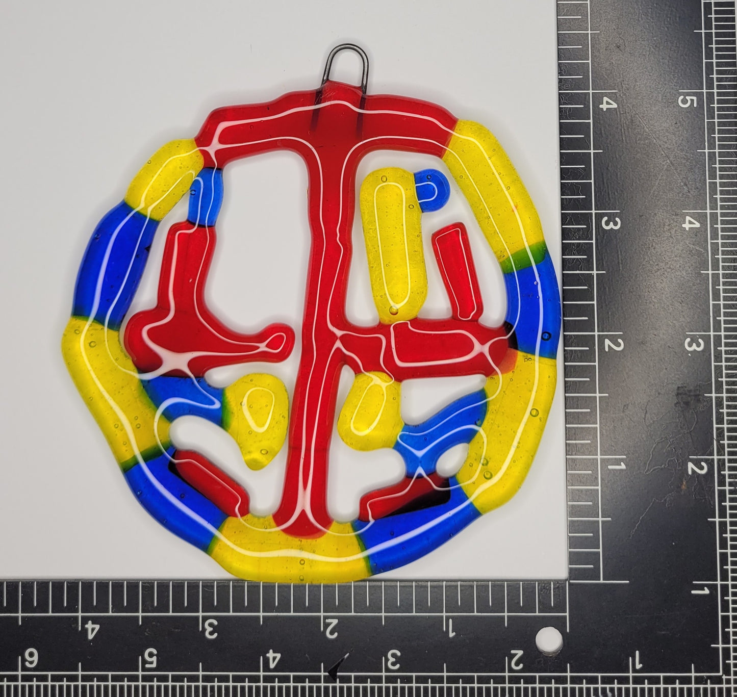 Colorful glass suncatcher with a ruler for scale on a gray background