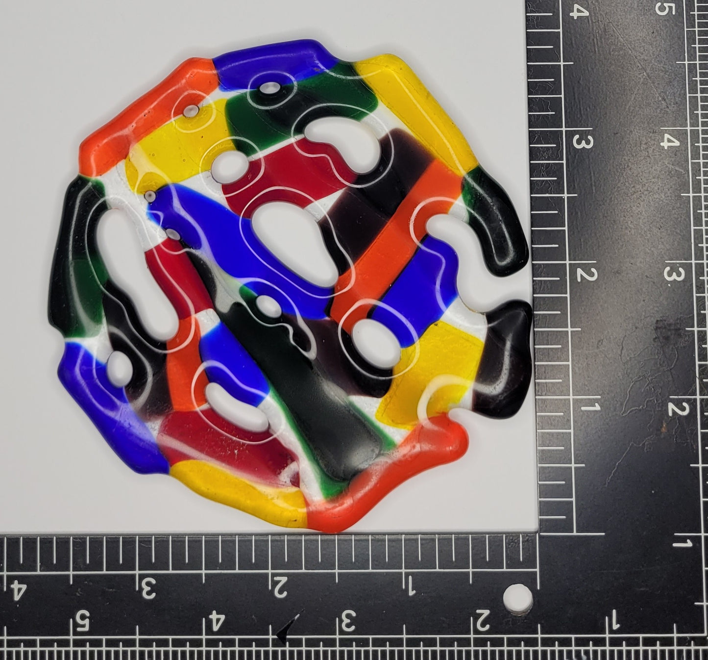 Colorful puzzle piece with a ruler for scale on a white background