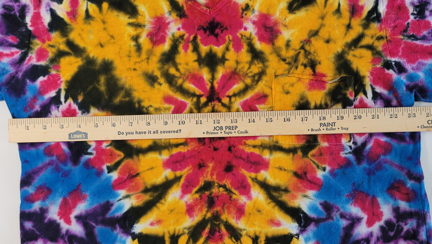 Tie-dye fabric with a ruler for scale, showing vibrant colors like yellow, pink, blue, and black.