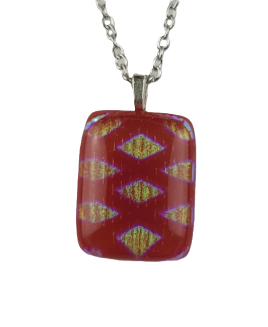 Red pendant with a pattern on a silver chain against a white background