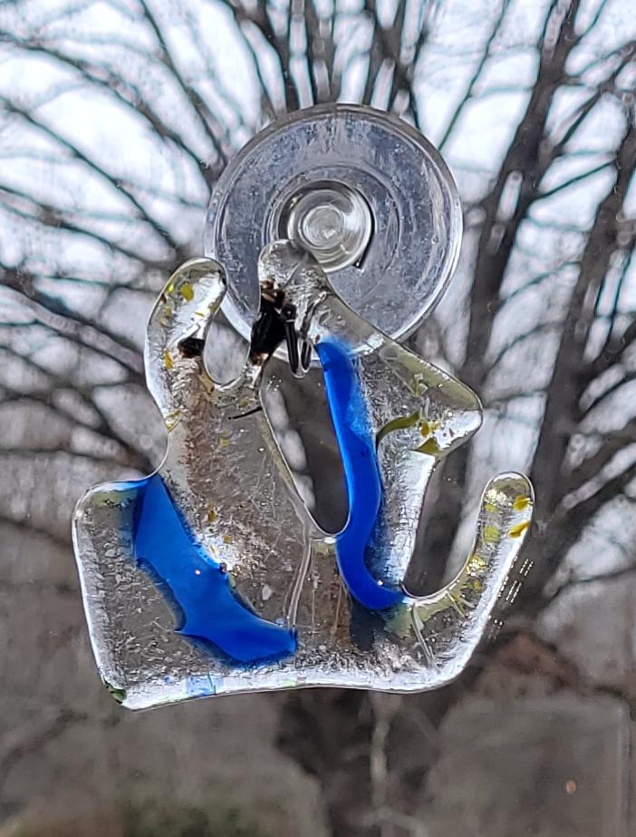 Clear glass suncatcher  with blue accents against a blurred natural background