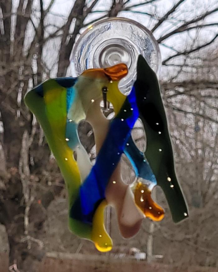 Colorful glass hanging decoration against a blurred natural background