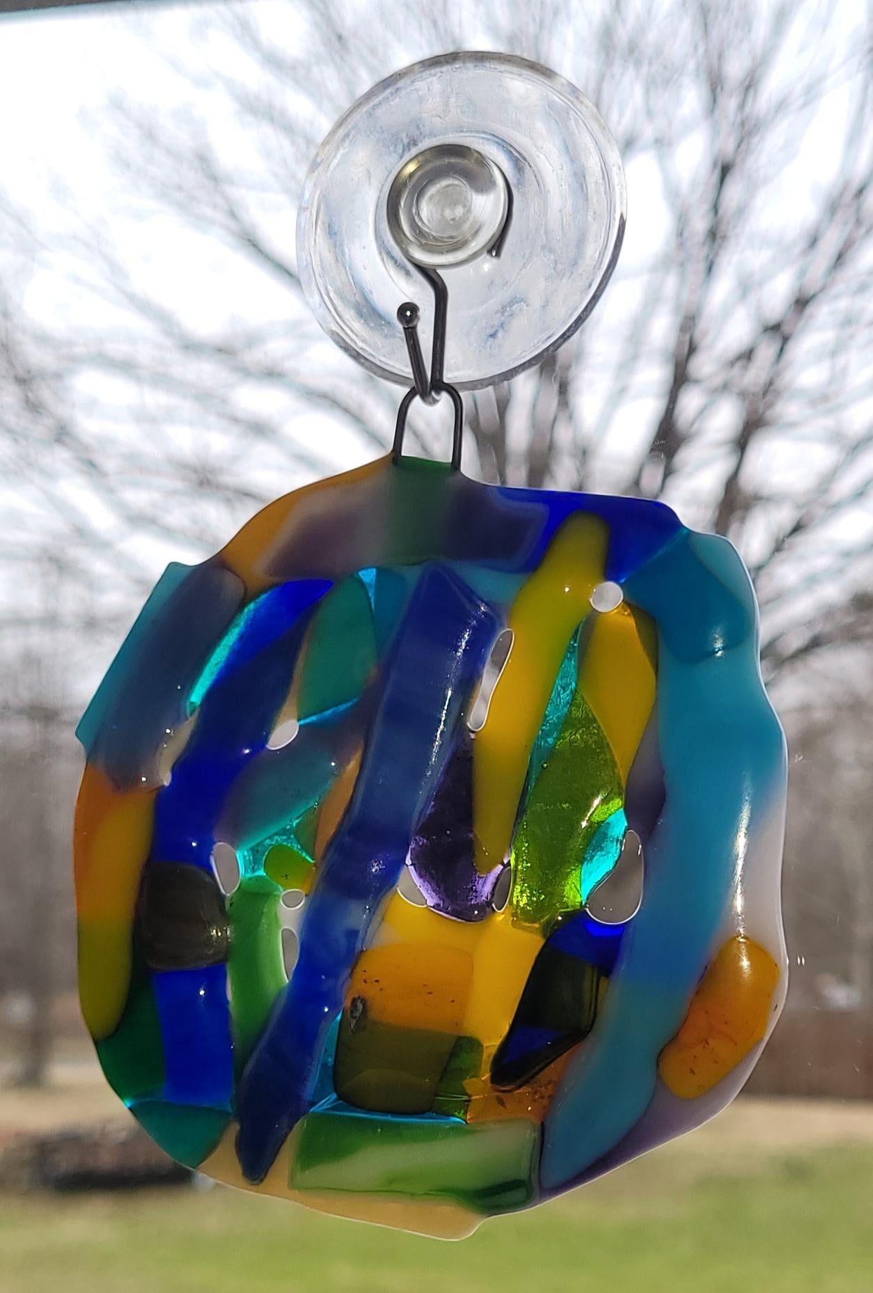 Colorful glass orb with a suction cup on a blurred outdoor background