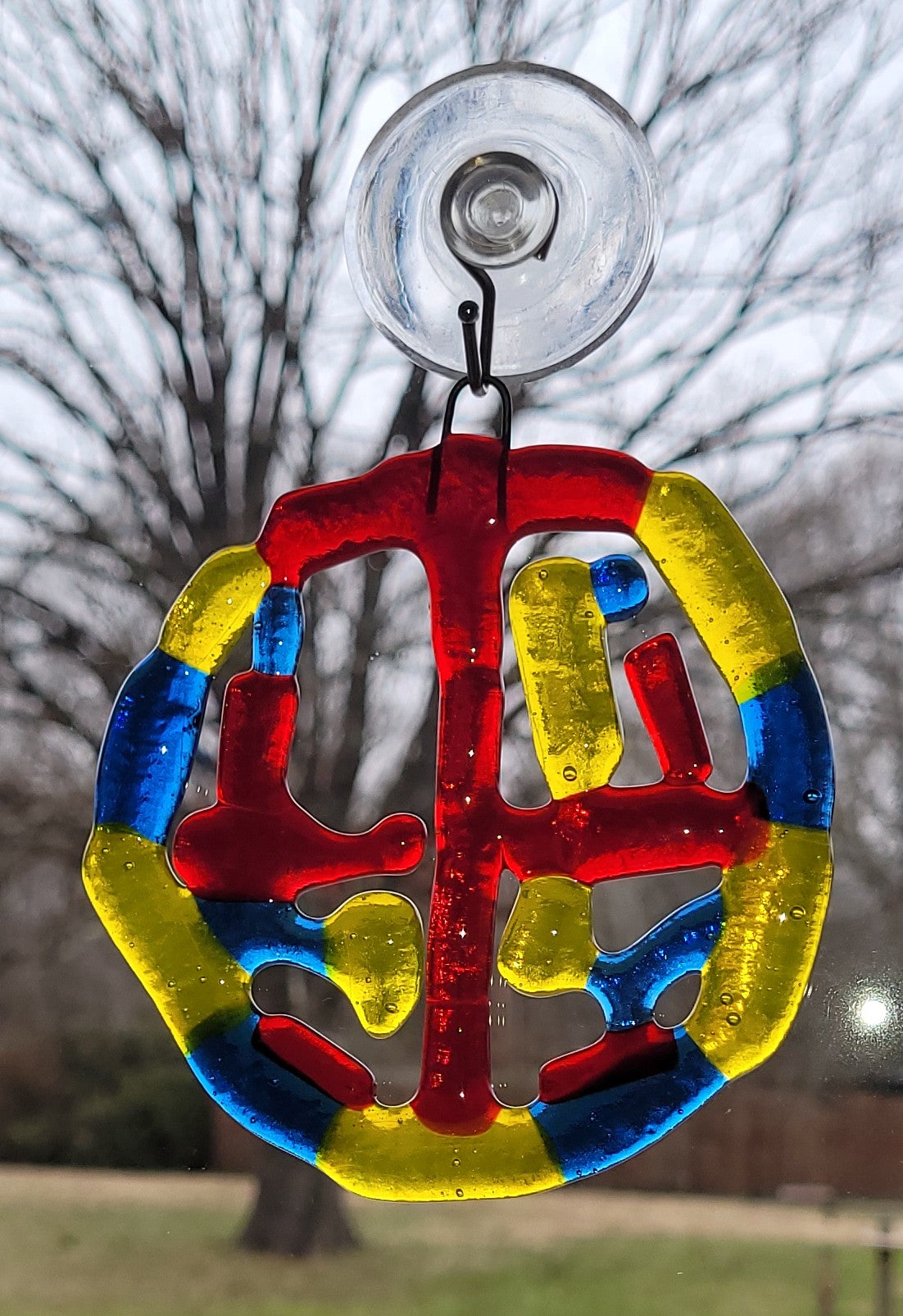Colorful suncatcher with suction cup against a blurred natural background
