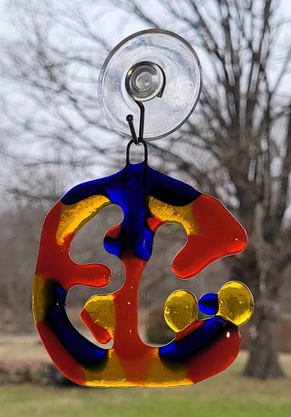 Colorful glass hanging ornament with suction cup against a blurred natural background