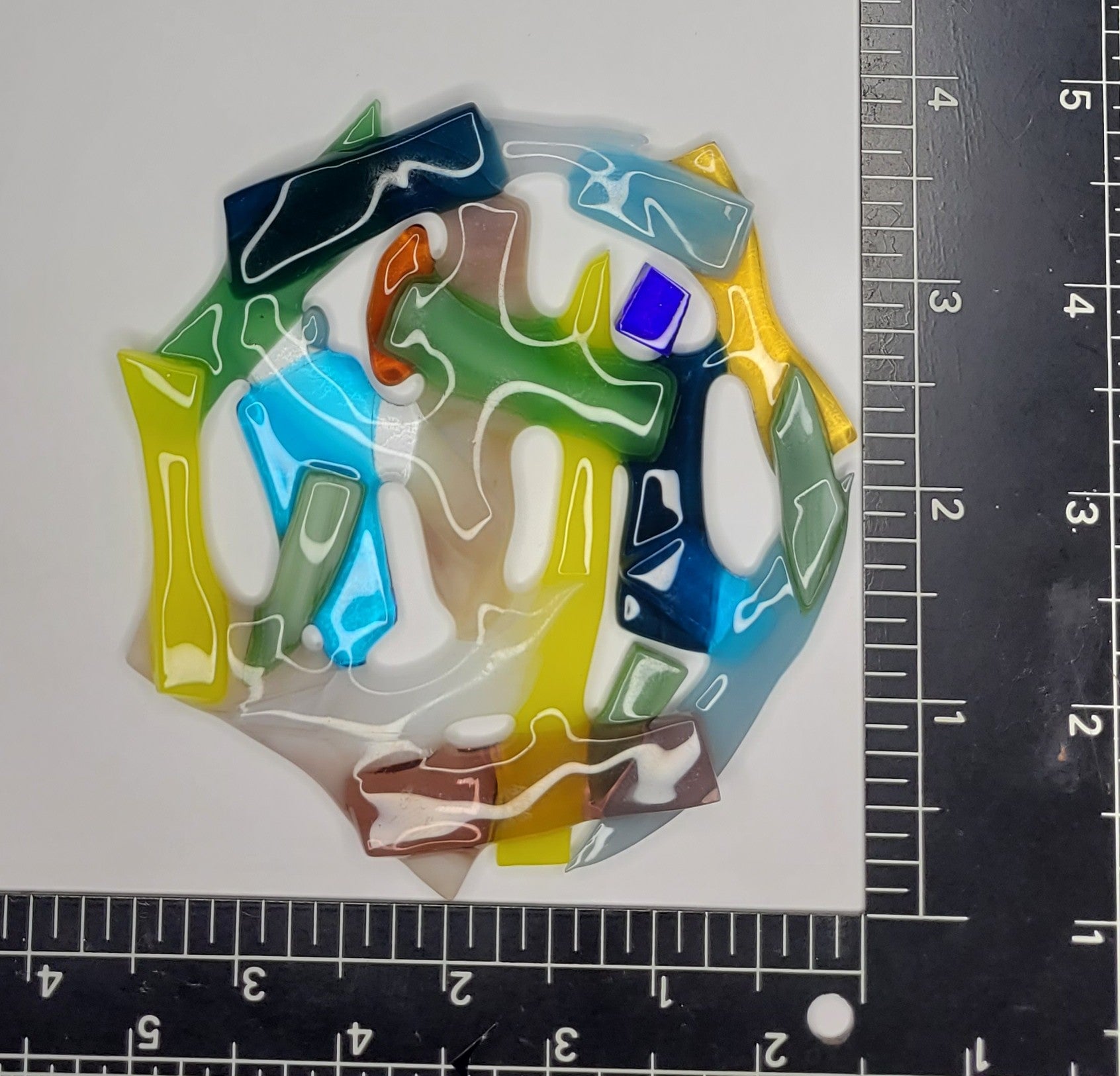 Colorful abstract art piece on a white background with a ruler for scale.