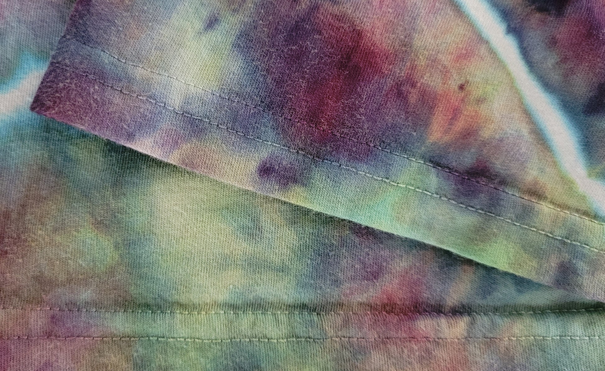 Close-up of tie-dye fabric with purple, green, and red colors.