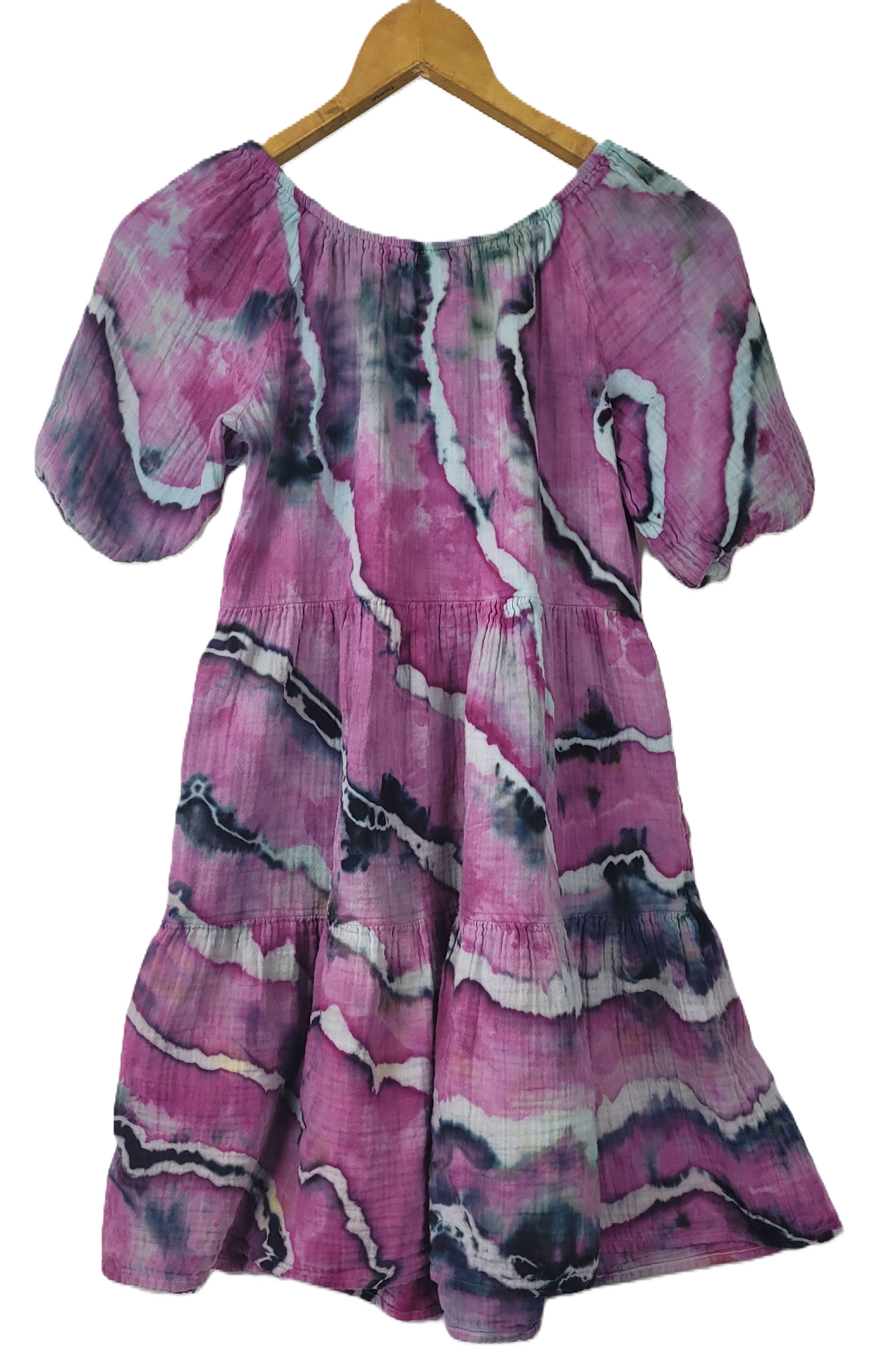 Pink and purple patterned dress on a wooden hanger against a white background