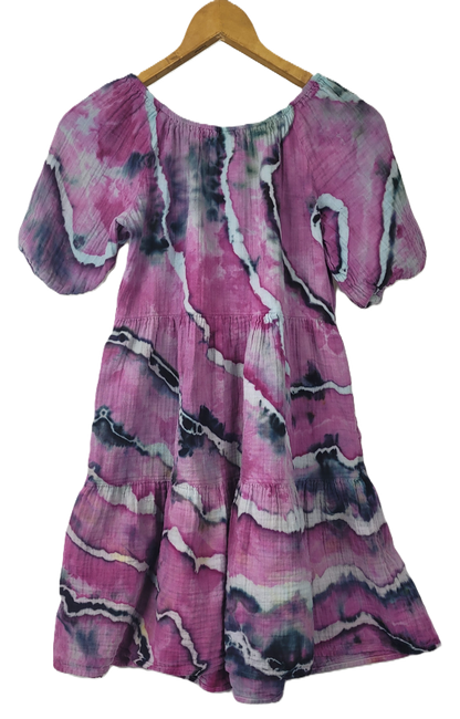 Pink and purple patterned dress on a wooden hanger against a white background