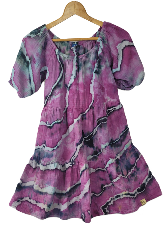 Pink patterned dress on a wooden hanger against a white background
