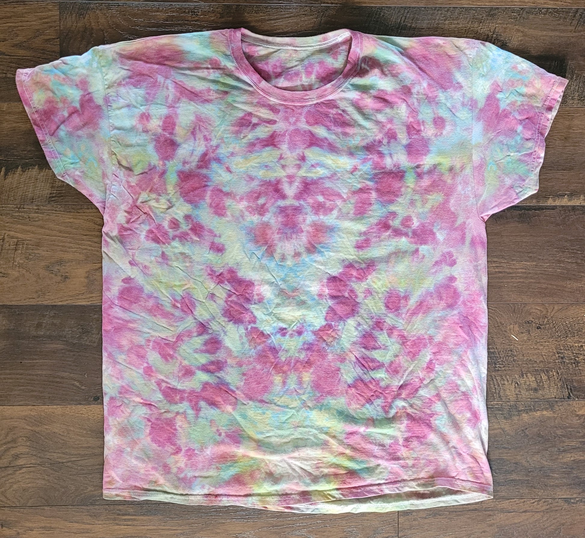 Tie-dye t-shirt with pink and green pattern on a wooden surface