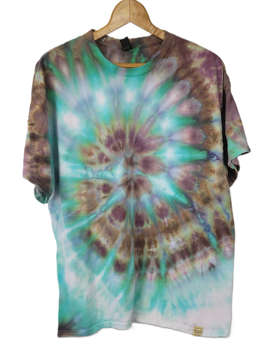Tie-dye shirt with a spiral pattern on a hanger against a white background