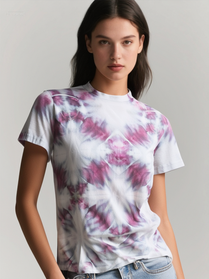 Person wearing a tie-dye t-shirt with pink and purple patterns on a plain background