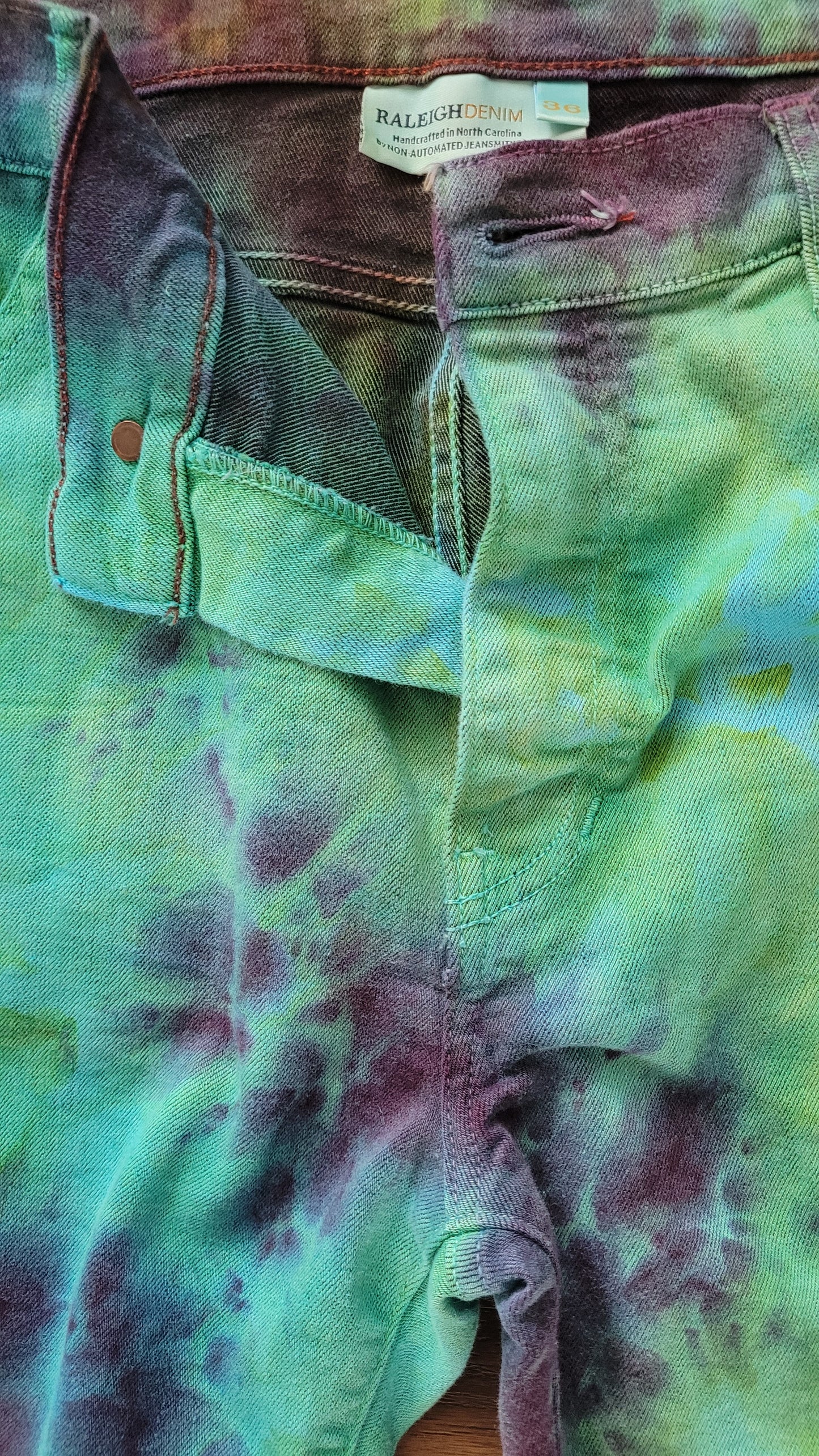 Close-up of a tie-dye jeans with a visible brand tag.