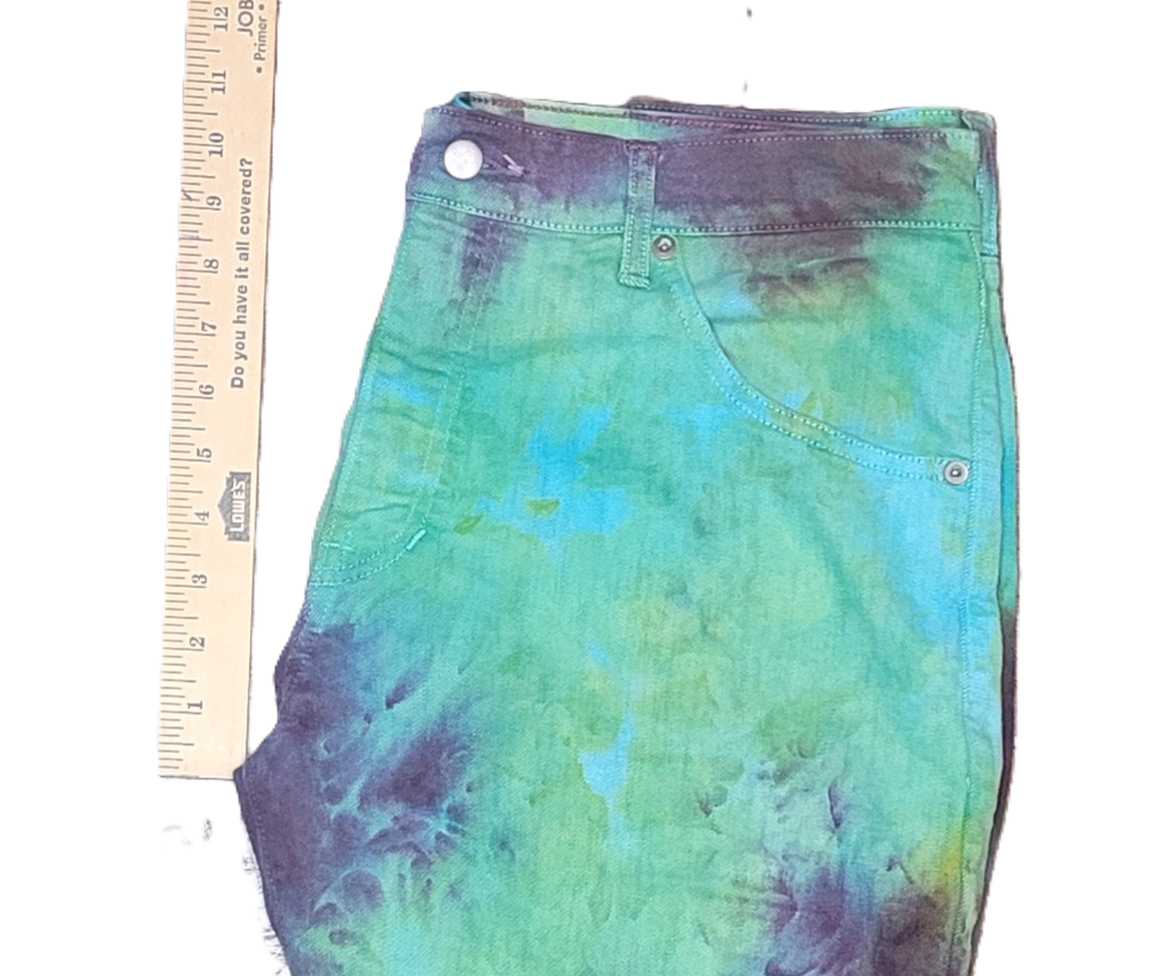 Tie-dye jeans with a ruler for scale on a white background