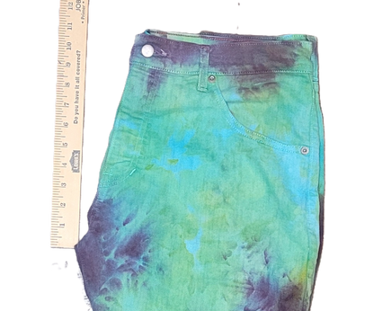 Tie-dye jeans with a ruler for scale on a white background