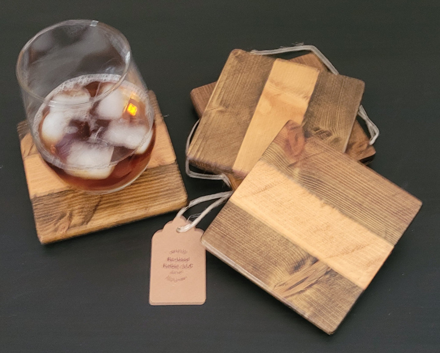 Set of wooden coasters with a glass of iced coffee on a dark surface