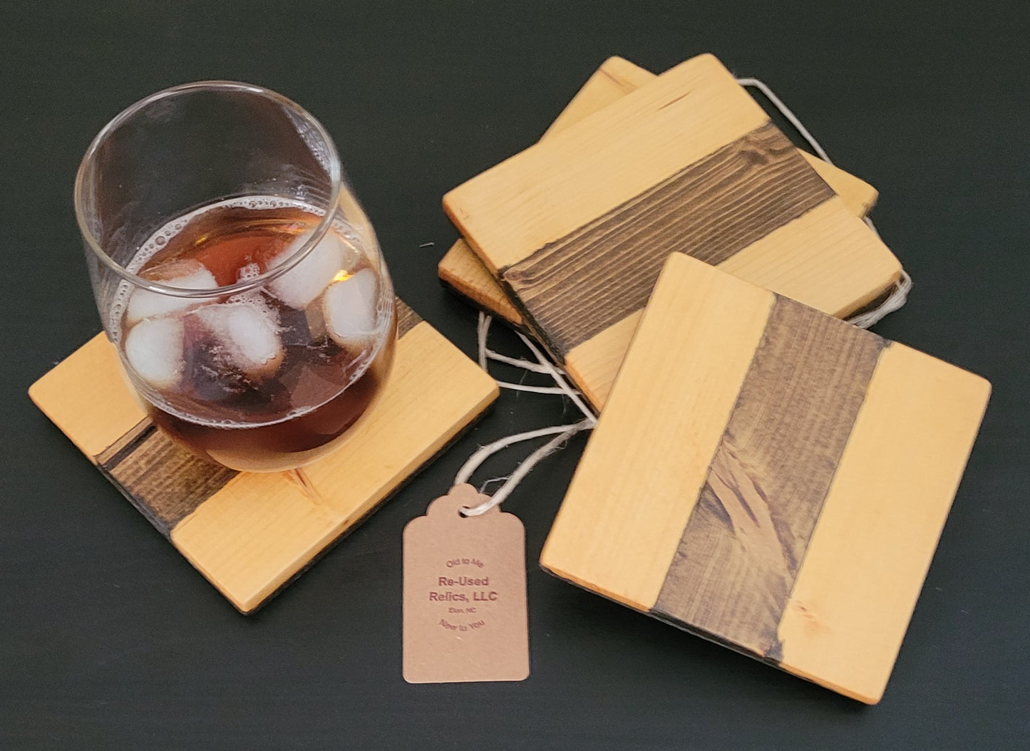 Wooden coasters with a glass of iced drink on a dark surface