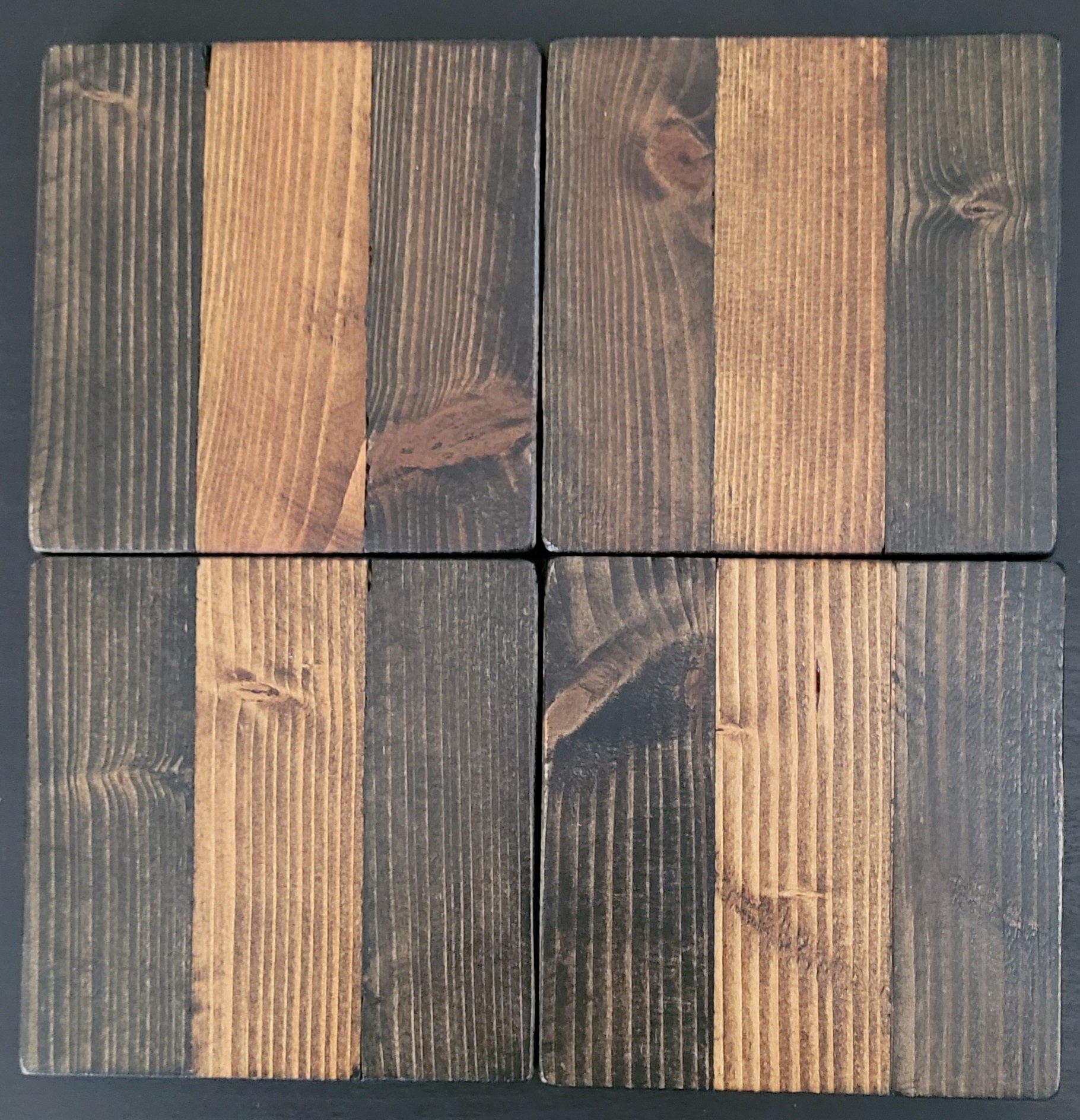Four wooden coasters with a natural, rustic finish on a dark background