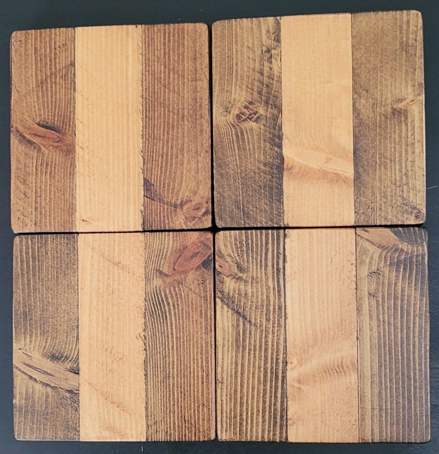 Four wooden coasters with a natural, rustic finish on a dark background