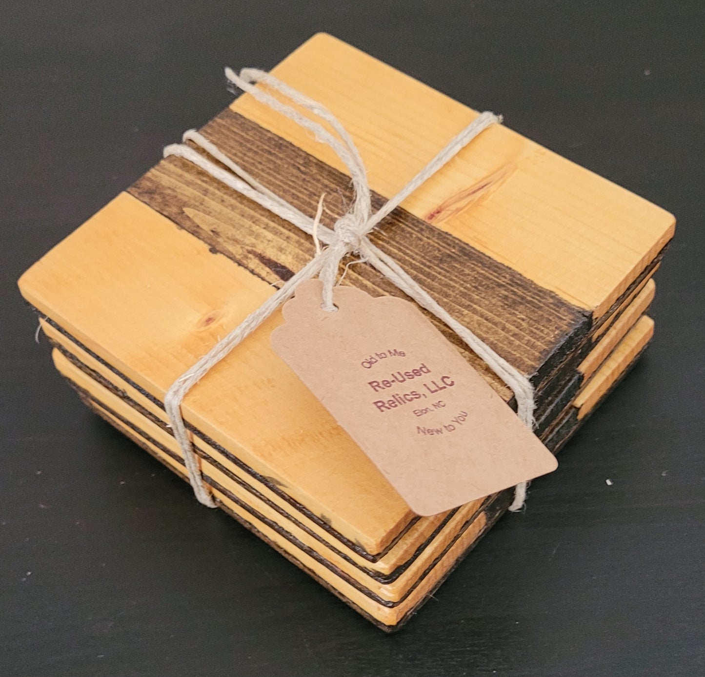 Stack of wooden coasters tied with string and a tag on a dark background