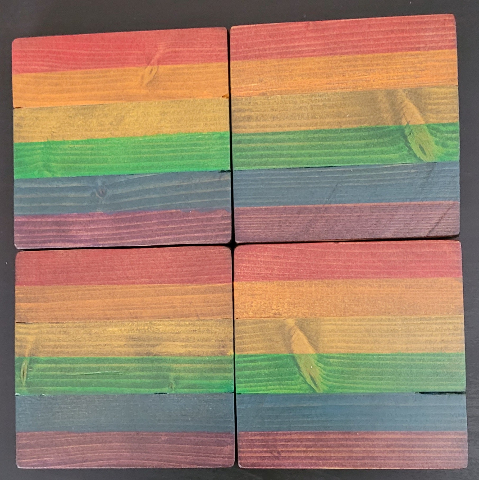 Four wooden blocks with rainbow striped pattern on a dark background