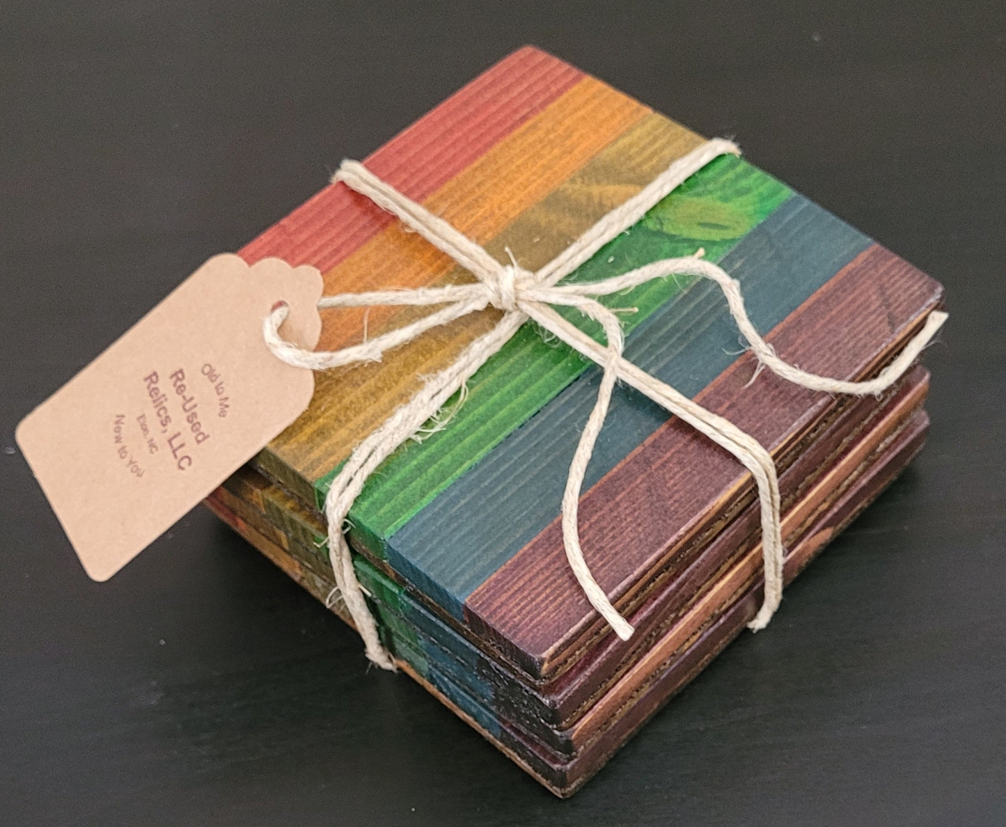 Stack of colorful wooden coasters tied with string on a dark background