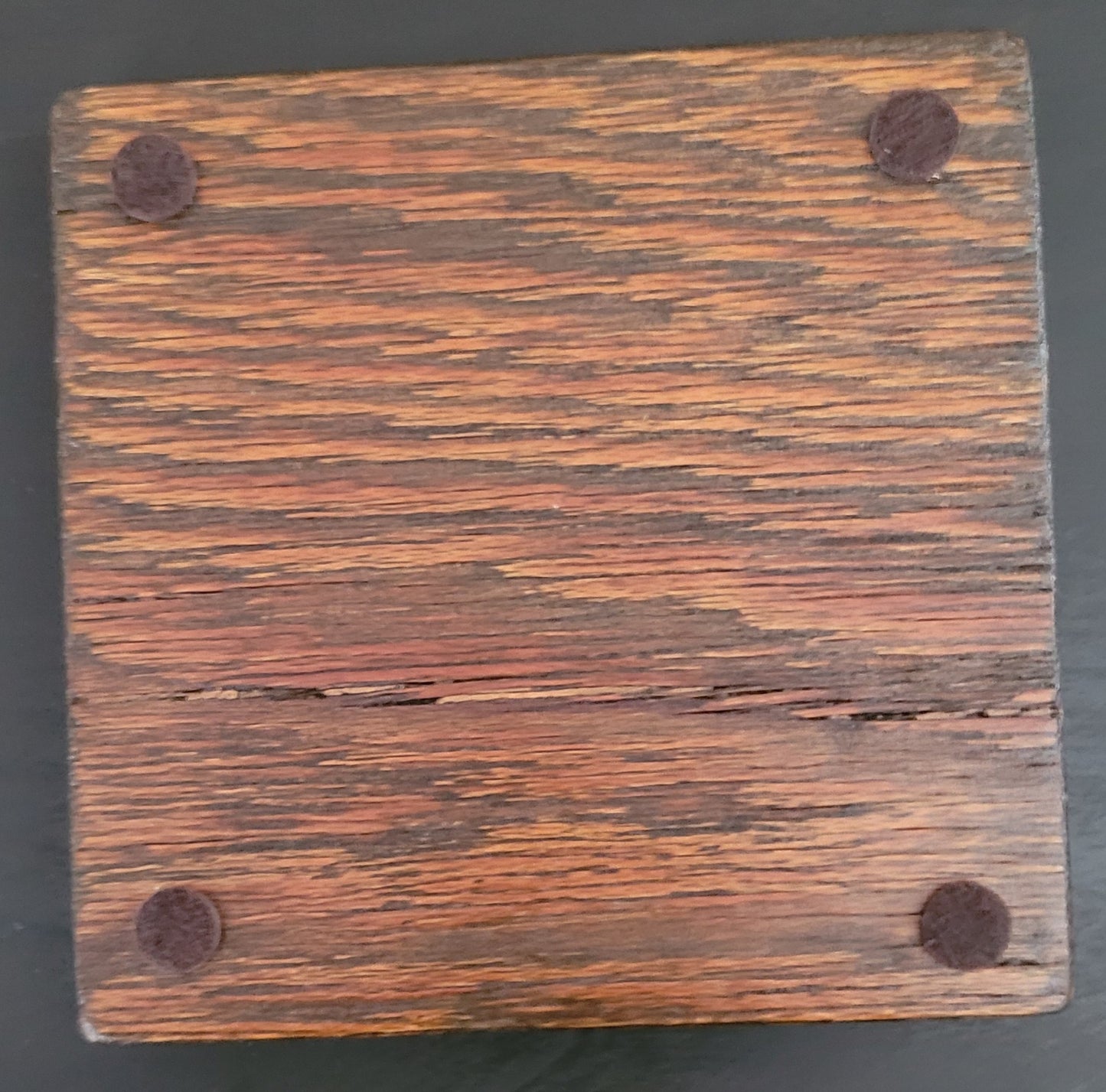 Bottom of a wooden coaster with four felt pads.