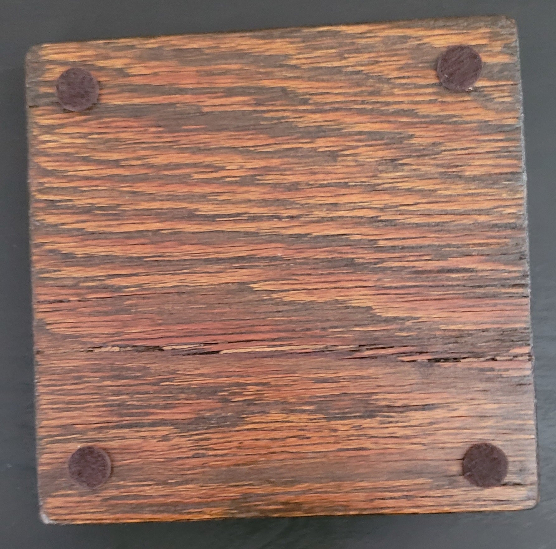 Bottom of a wooden coaster with four felt pads.
