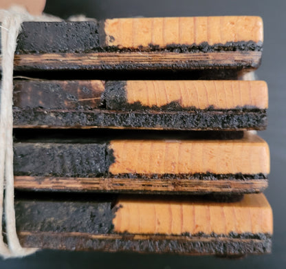 Close-up the side of a stack of wooden coasters tied with string on a dark surface