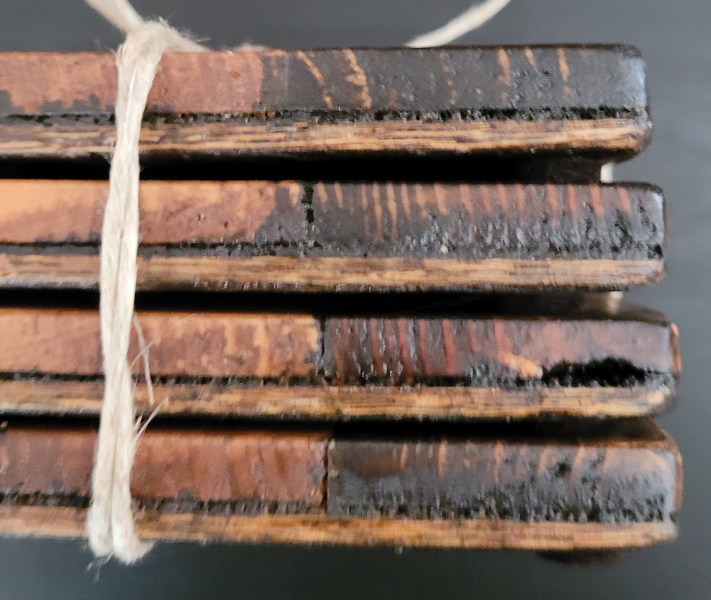 Close-up of stack of wooden coasters side tied with string on a dark surface