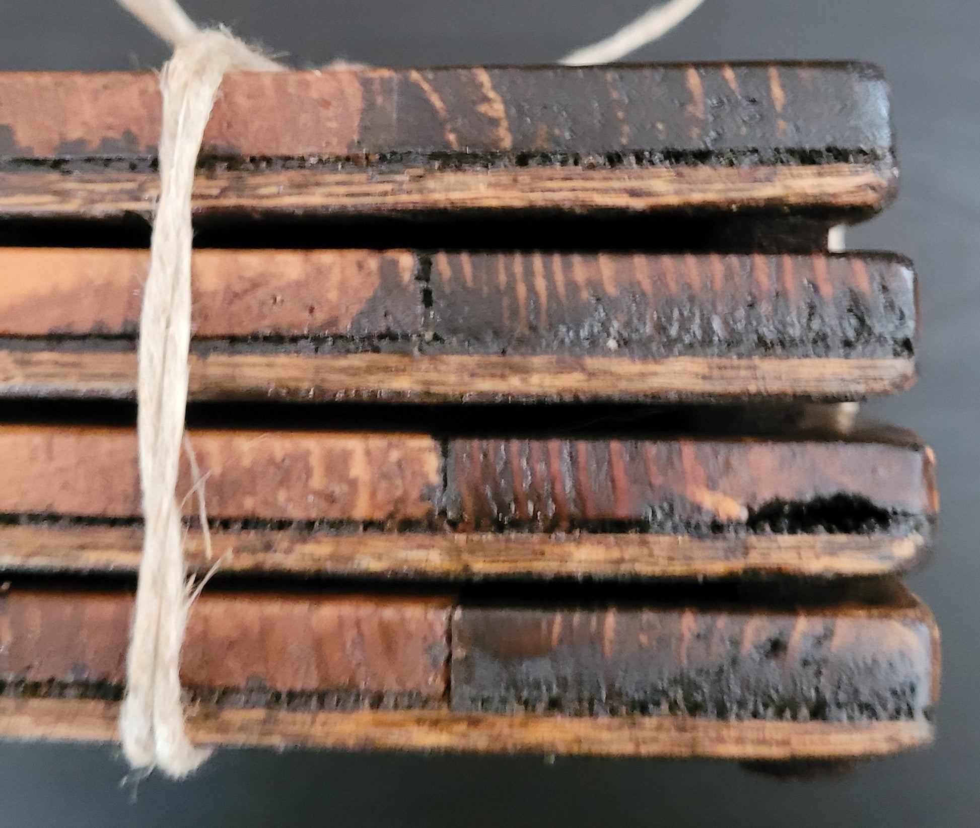 Close-up of stack of wooden coasters side tied with string on a dark surface