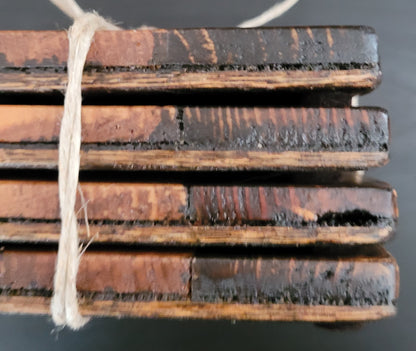 Close-up of stack of wooden coasters side tied with string on a dark surface