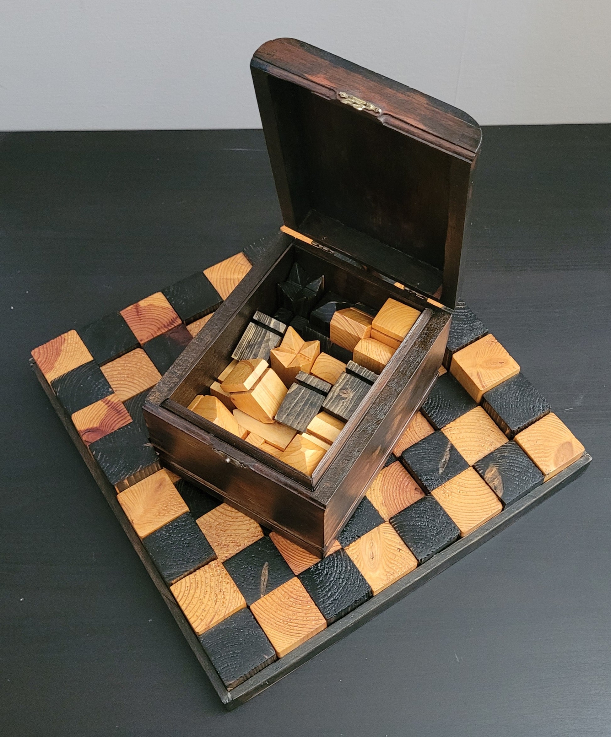Wooden chess set with pieces and a checkered board on a dark surface.