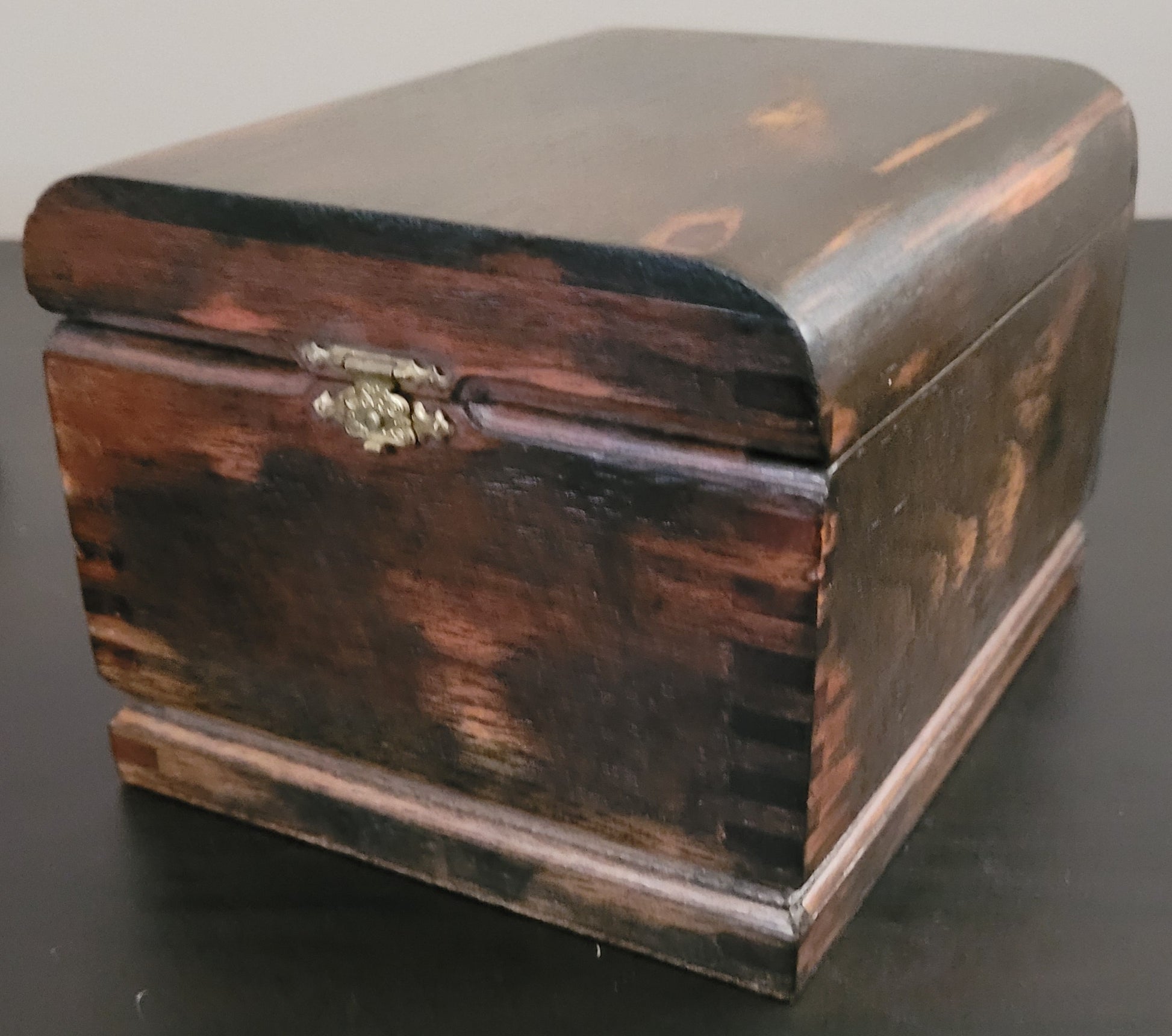 Wooden box with a decorative clasp on a dark surface