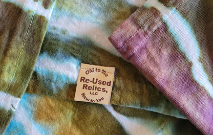 Close-up of a tie-dye shirt with a label reading 'Re-Used Relics, LLC' on a multicolored background.