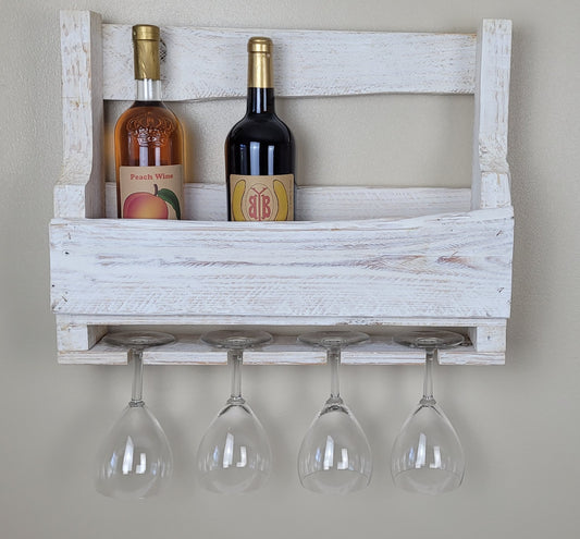 Wooden wine rack with two bottles and four glasses on a plain wall.