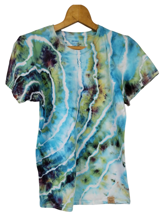 Tie-dye t-shirt with blue, green, and white patterns on a wooden hanger.
