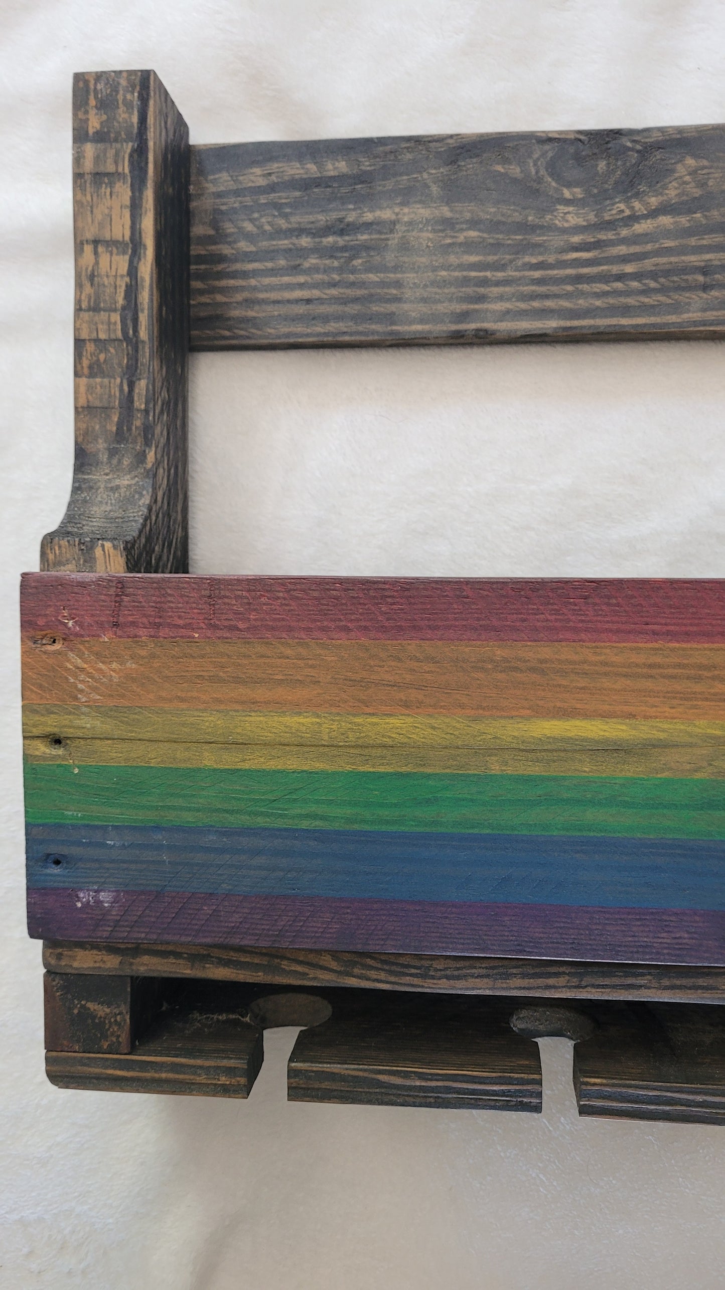 Wooden wine rack with rainbow-colored slats on a white background
